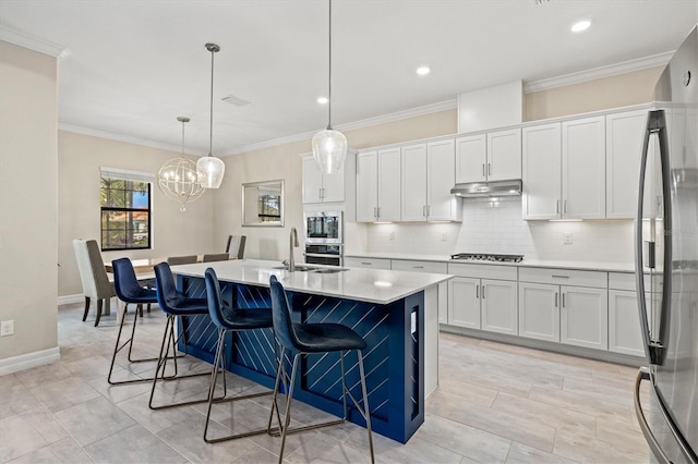 kitchen featuring light countertops, appliances with stainless steel finishes, white cabinets, a sink, and under cabinet range hood