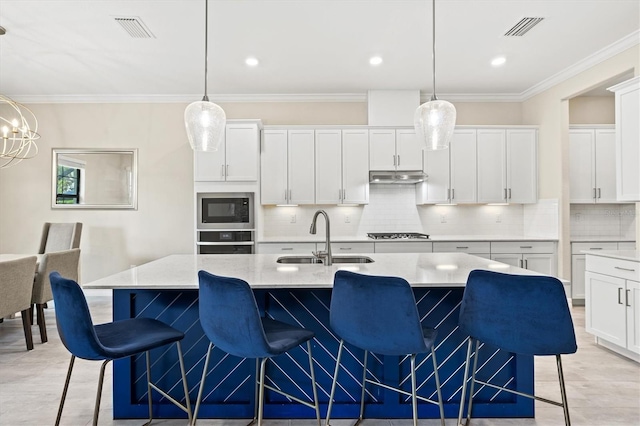 kitchen with under cabinet range hood, a sink, visible vents, ornamental molding, and appliances with stainless steel finishes