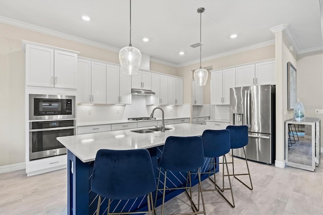 kitchen featuring appliances with stainless steel finishes, ornamental molding, white cabinets, a sink, and under cabinet range hood