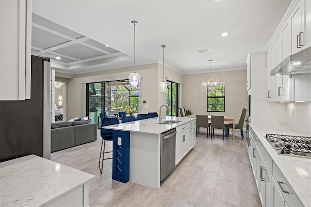 kitchen with decorative backsplash, open floor plan, stainless steel appliances, white cabinetry, and a sink