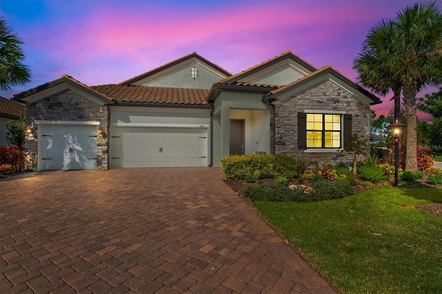 ranch-style home with decorative driveway, stucco siding, a lawn, an attached garage, and stone siding