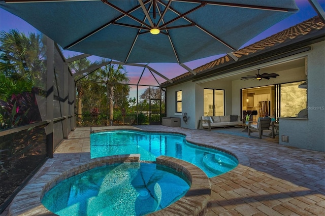 view of pool with glass enclosure, ceiling fan, a patio area, a pool with connected hot tub, and an outdoor living space