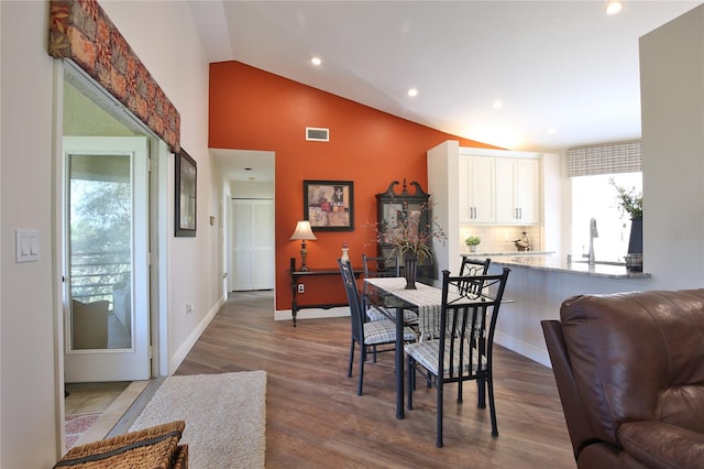 dining area with lofted ceiling, dark wood-type flooring, and sink