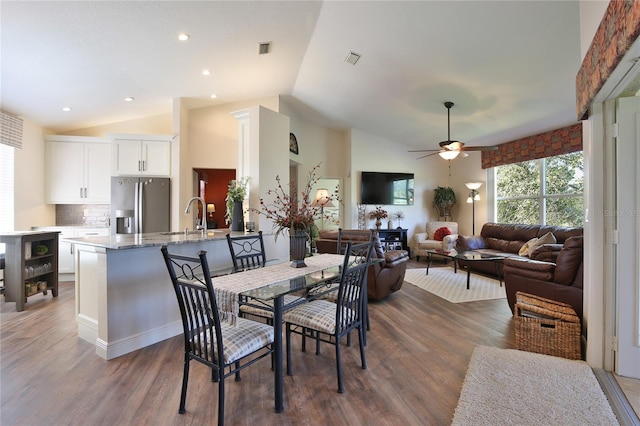 dining space with sink, ceiling fan, vaulted ceiling, and dark hardwood / wood-style flooring