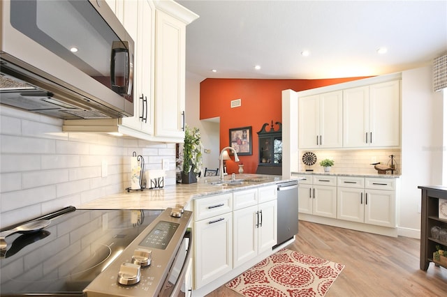 kitchen featuring lofted ceiling, decorative backsplash, appliances with stainless steel finishes, and white cabinetry