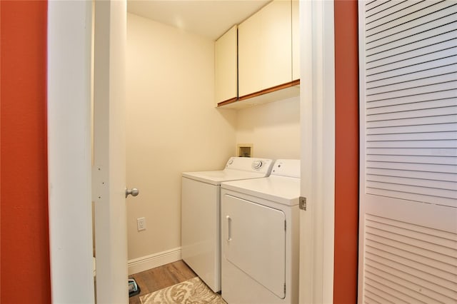 laundry room featuring washer and clothes dryer, cabinets, and light hardwood / wood-style floors