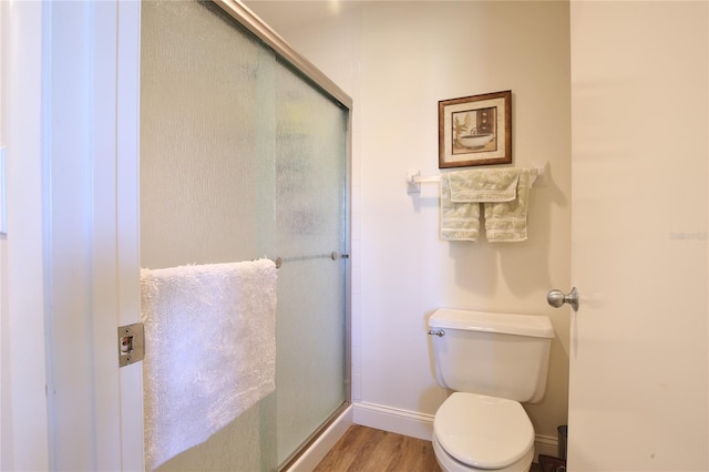 bathroom featuring an enclosed shower, toilet, and wood-type flooring