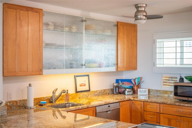 kitchen with light stone counters, ceiling fan, stainless steel appliances, and sink