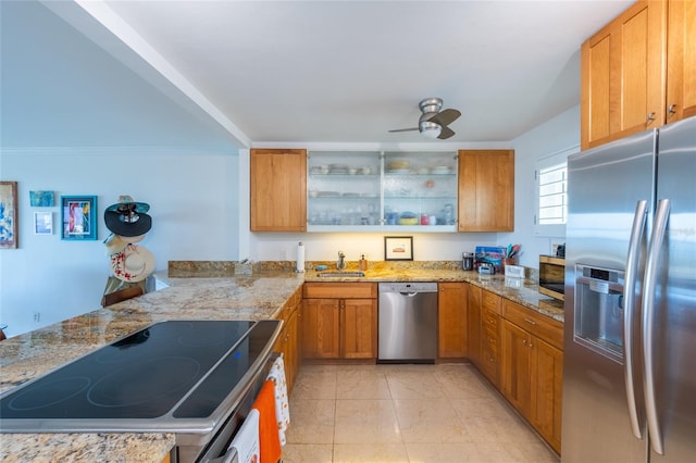 kitchen featuring kitchen peninsula, sink, ceiling fan, light stone counters, and stainless steel appliances