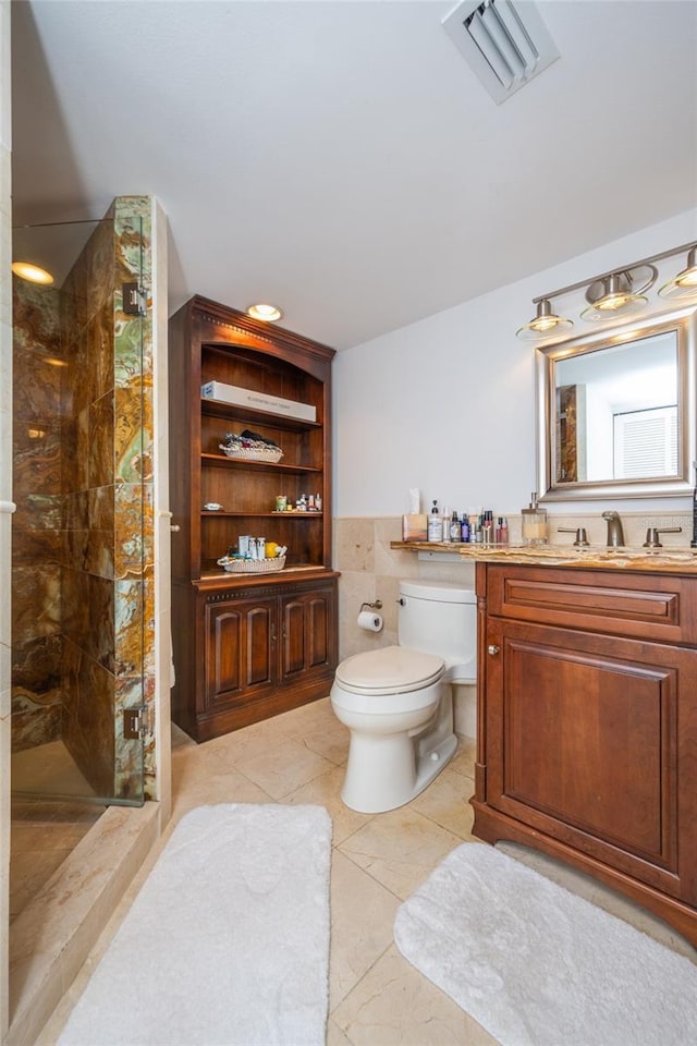 bathroom with vanity, tiled shower, tile patterned floors, and toilet