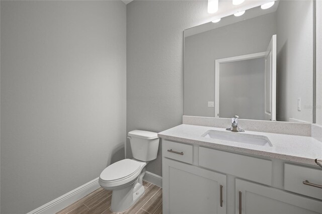 bathroom with vanity, toilet, and hardwood / wood-style flooring