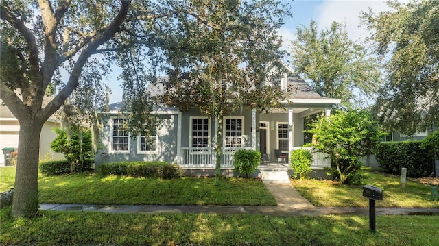 obstructed view of property with stucco siding, covered porch, and a front yard
