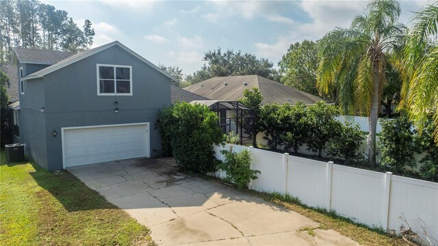 view of front of property featuring central AC, fence, roof with shingles, stucco siding, and concrete driveway