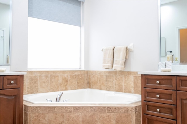 bathroom with vanity and tiled tub