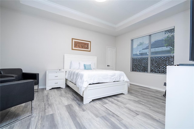 bedroom with crown molding, light wood-type flooring, and a raised ceiling