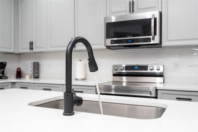 kitchen featuring sink, appliances with stainless steel finishes, backsplash, and white cabinets