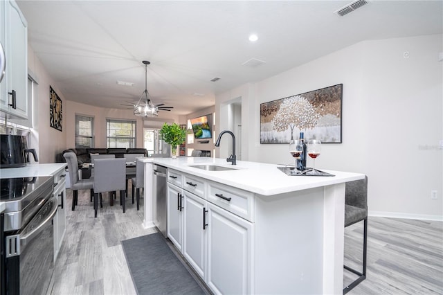 kitchen with ceiling fan, appliances with stainless steel finishes, an island with sink, light wood-type flooring, and sink