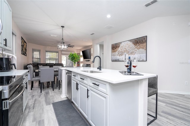 kitchen with appliances with stainless steel finishes, sink, ceiling fan, light hardwood / wood-style floors, and a kitchen island with sink