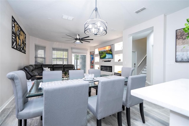 dining room with light hardwood / wood-style flooring, a textured ceiling, and ceiling fan with notable chandelier