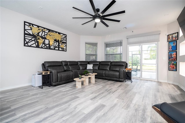 living room with light hardwood / wood-style flooring, a textured ceiling, and ceiling fan