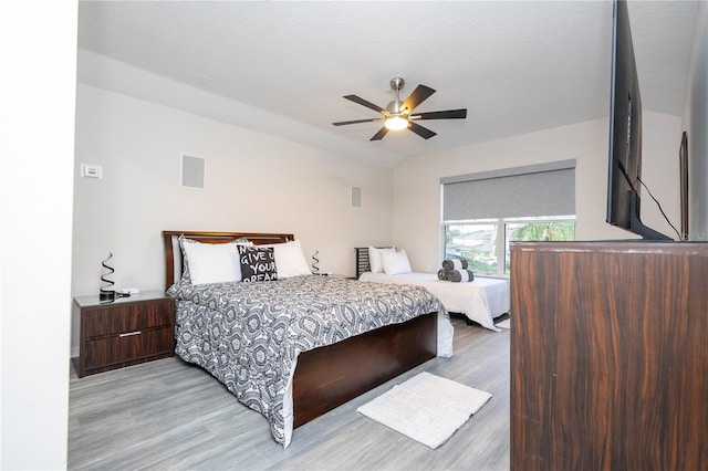 bedroom with vaulted ceiling, light wood-type flooring, and ceiling fan