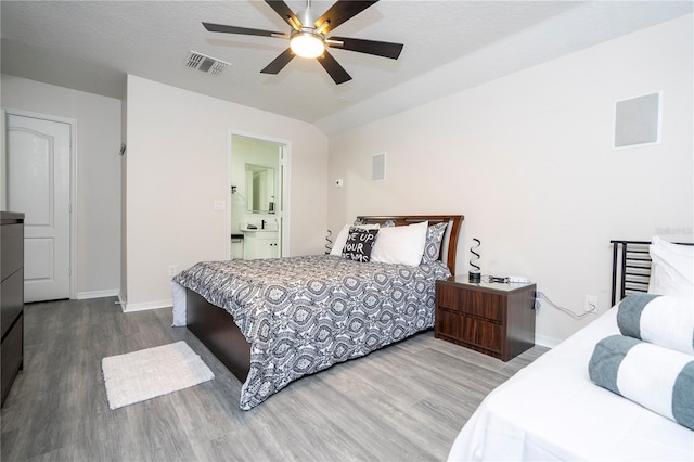 bedroom with ceiling fan, hardwood / wood-style flooring, a textured ceiling, and ensuite bath