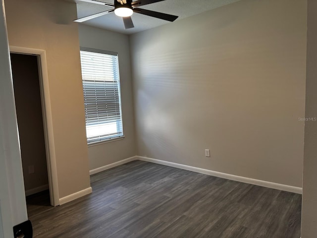 spare room with ceiling fan, baseboards, and dark wood-type flooring