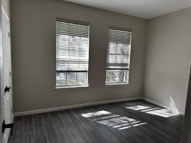 spare room with baseboards and wood finished floors