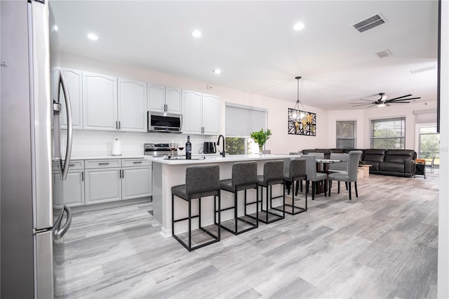 kitchen with a kitchen breakfast bar, visible vents, appliances with stainless steel finishes, open floor plan, and recessed lighting