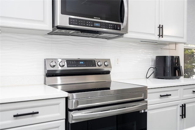 kitchen featuring white cabinets, appliances with stainless steel finishes, decorative backsplash, and light countertops