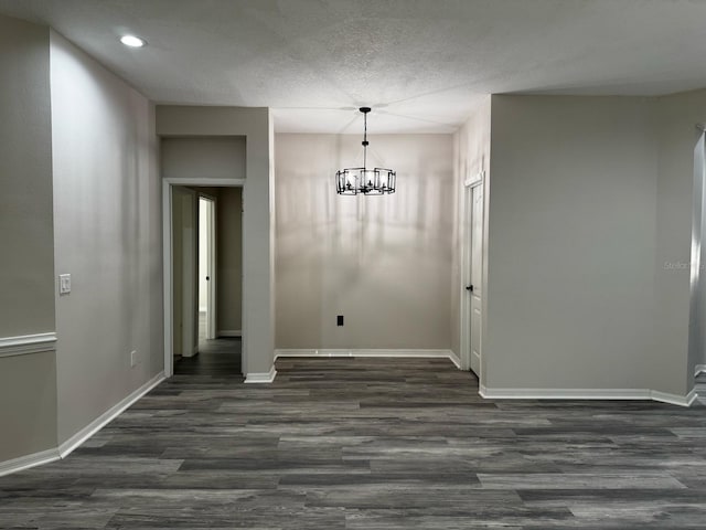 unfurnished dining area featuring recessed lighting, baseboards, an inviting chandelier, and dark wood-style floors