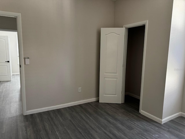 empty room featuring baseboards and dark wood-style flooring