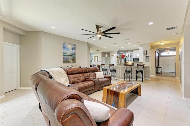 living room with ceiling fan, light tile patterned floors, and a textured ceiling