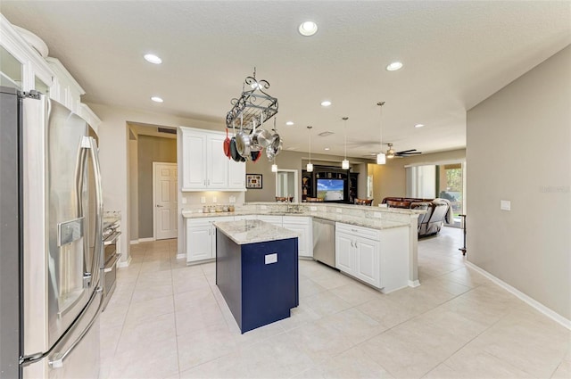 kitchen with kitchen peninsula, appliances with stainless steel finishes, a center island, and white cabinetry