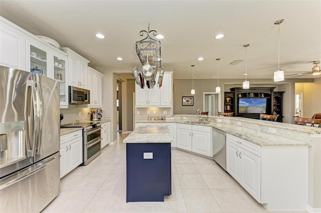 kitchen featuring kitchen peninsula, appliances with stainless steel finishes, sink, white cabinets, and a center island