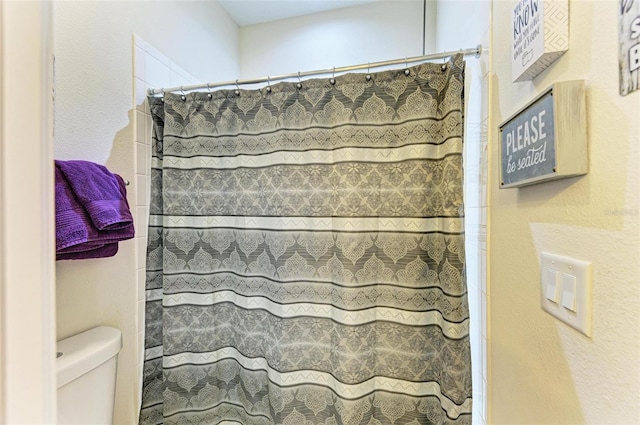 bathroom featuring walk in shower and toilet