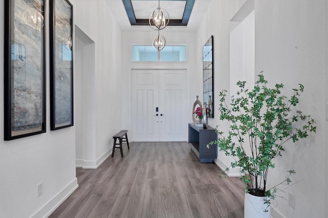 entryway with a notable chandelier, hardwood / wood-style floors, and a tray ceiling