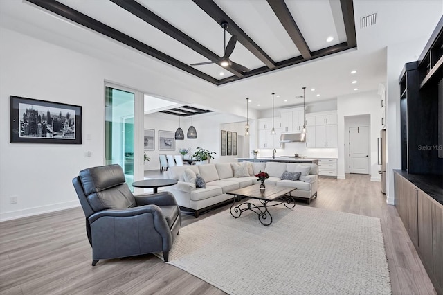 living room with beam ceiling, sink, and light wood-type flooring