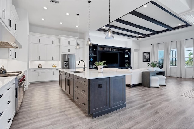 kitchen featuring a large island, sink, decorative light fixtures, premium appliances, and white cabinets