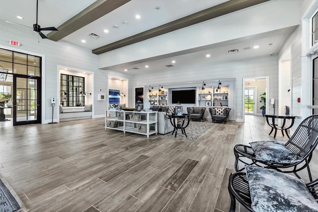 living room with beamed ceiling, wooden walls, hardwood / wood-style flooring, and ceiling fan