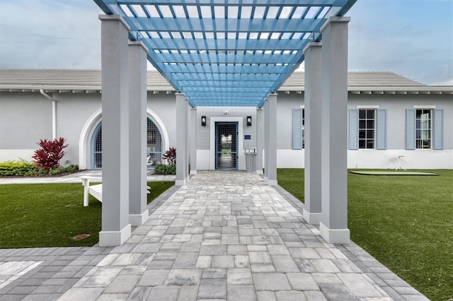 entrance to property with a yard and a pergola