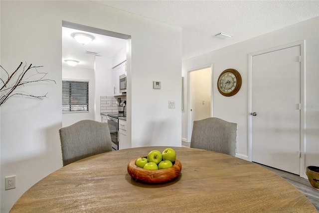 dining space featuring light wood-type flooring and a textured ceiling