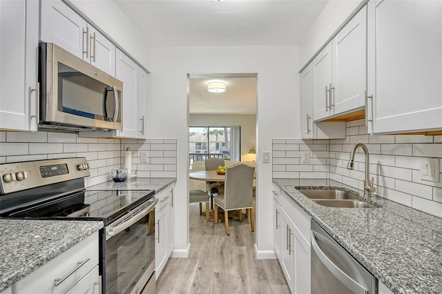 kitchen with white cabinetry, sink, light hardwood / wood-style floors, and appliances with stainless steel finishes