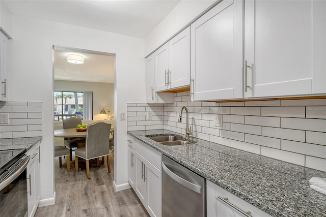 kitchen featuring white cabinets, decorative backsplash, appliances with stainless steel finishes, and light hardwood / wood-style flooring