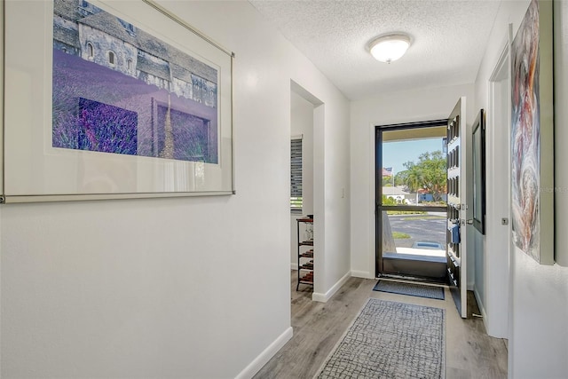 entryway with a textured ceiling and light wood-type flooring