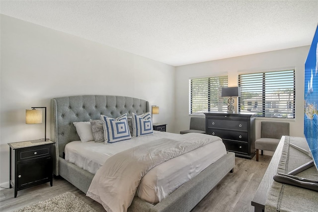 bedroom with light hardwood / wood-style floors and a textured ceiling