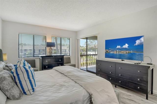 bedroom with light wood-type flooring, a textured ceiling, access to outside, and multiple windows