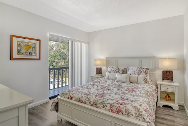 bedroom featuring access to exterior, hardwood / wood-style floors, and a textured ceiling