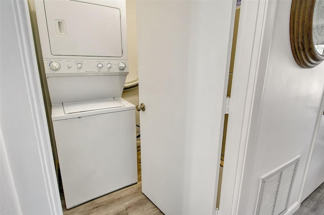 clothes washing area featuring stacked washer / dryer and light wood-type flooring