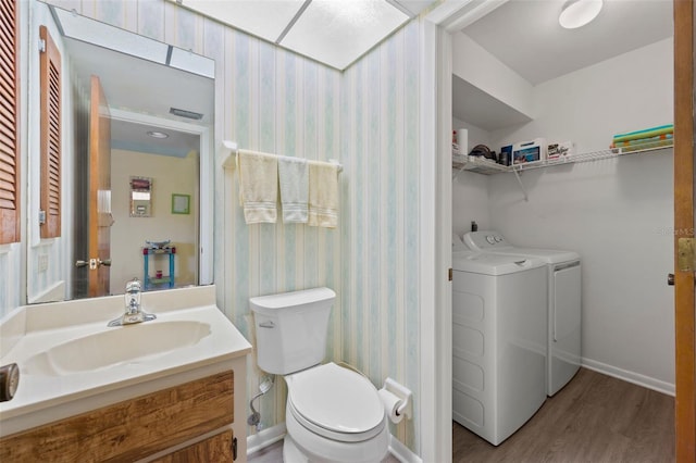 bathroom featuring vanity, hardwood / wood-style floors, toilet, and washing machine and dryer